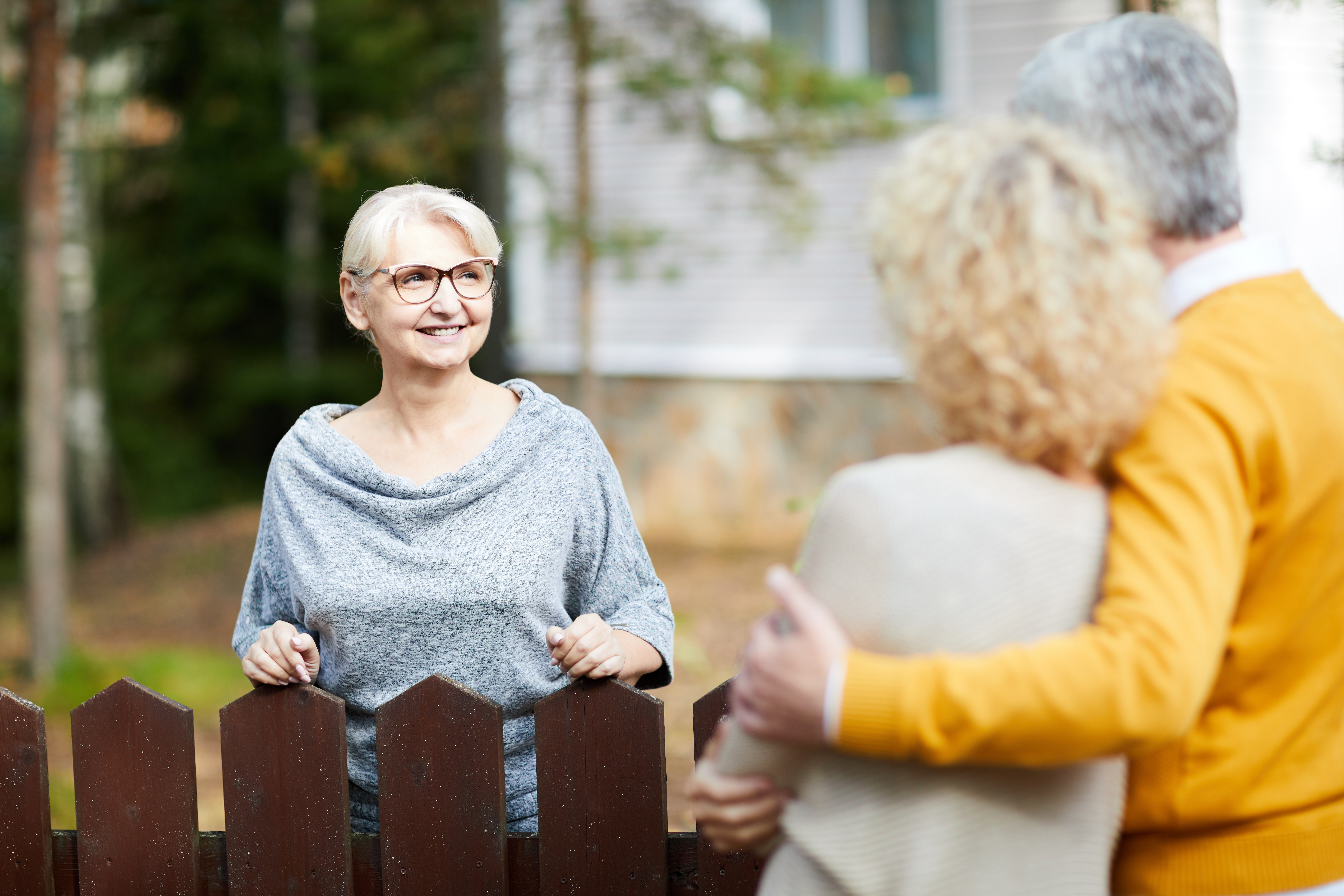 neighbors smile at each other across a fence