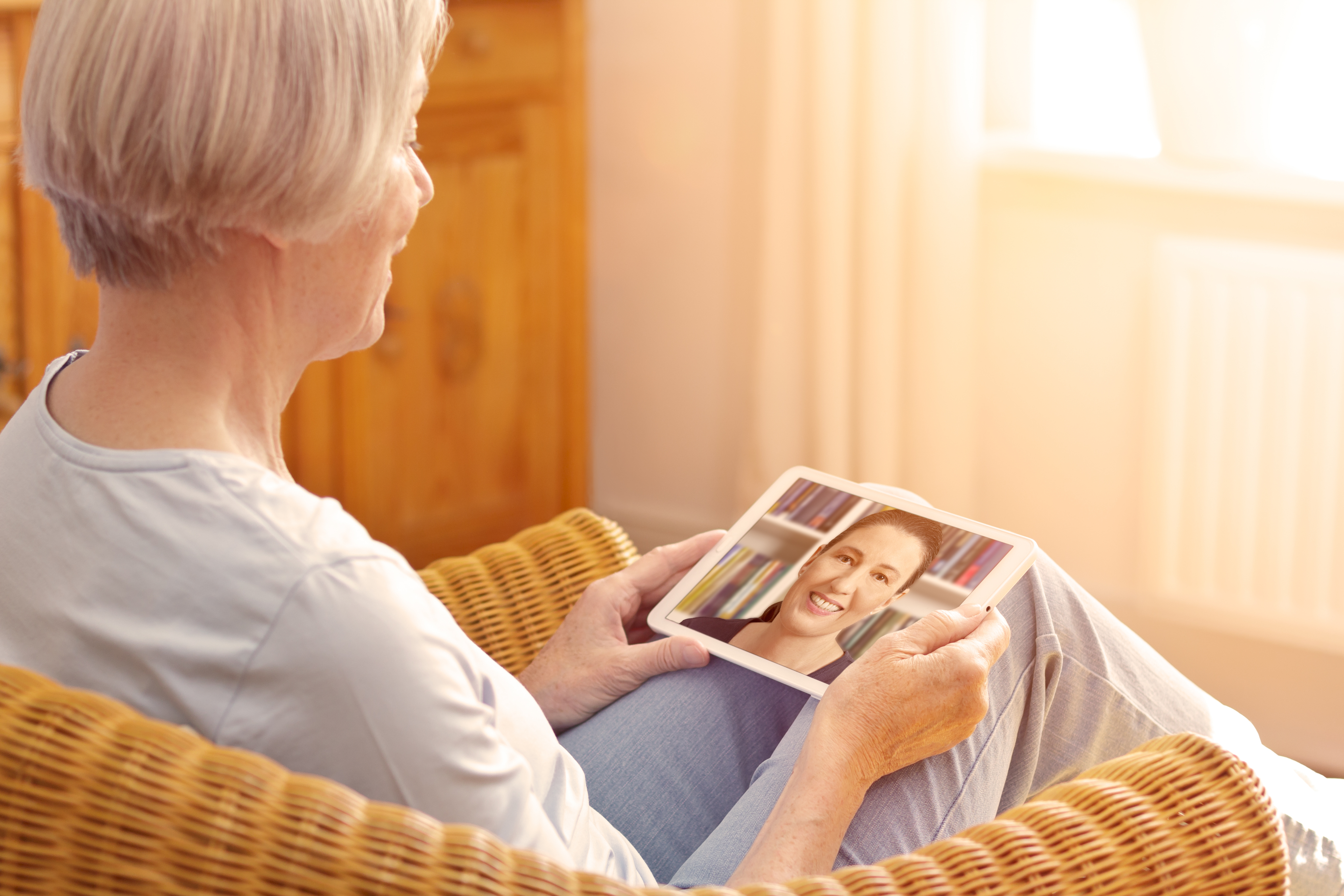 older adult woman Facetiming her daughter on tablet