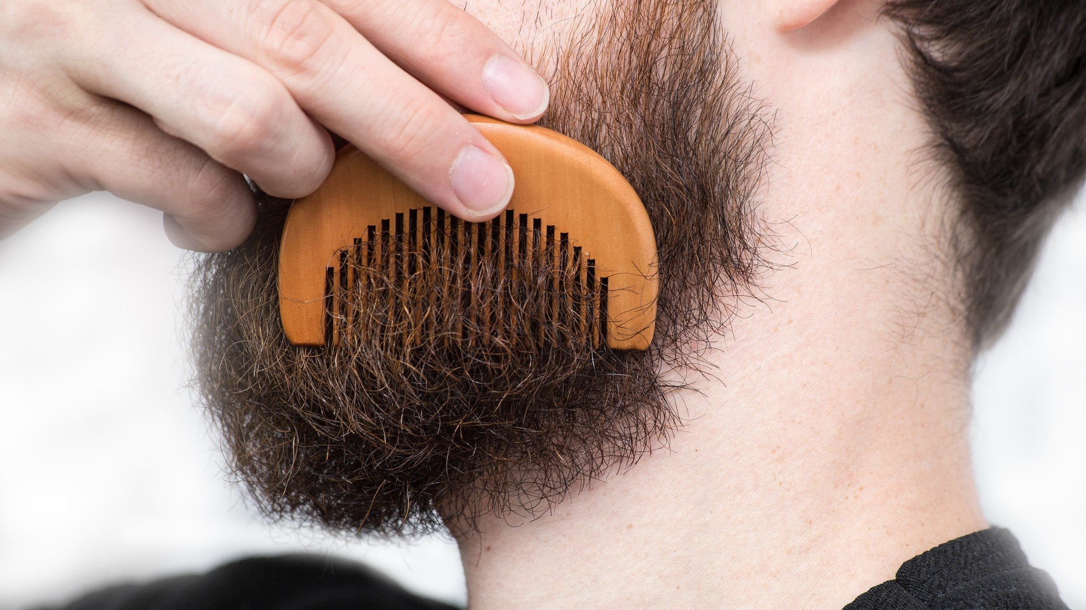 Man using a comb on his beard.