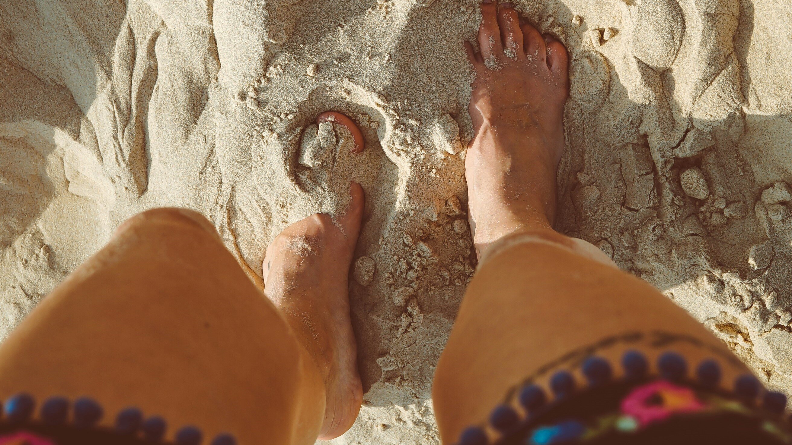 feet in sand at beach