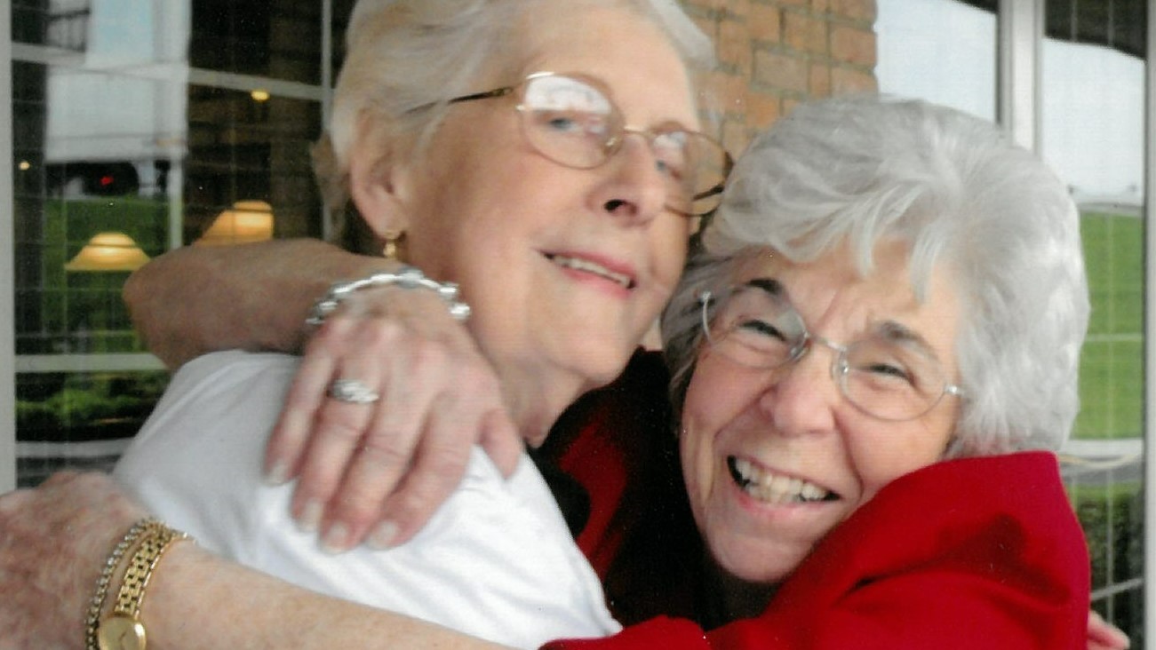two older adult friends hugging