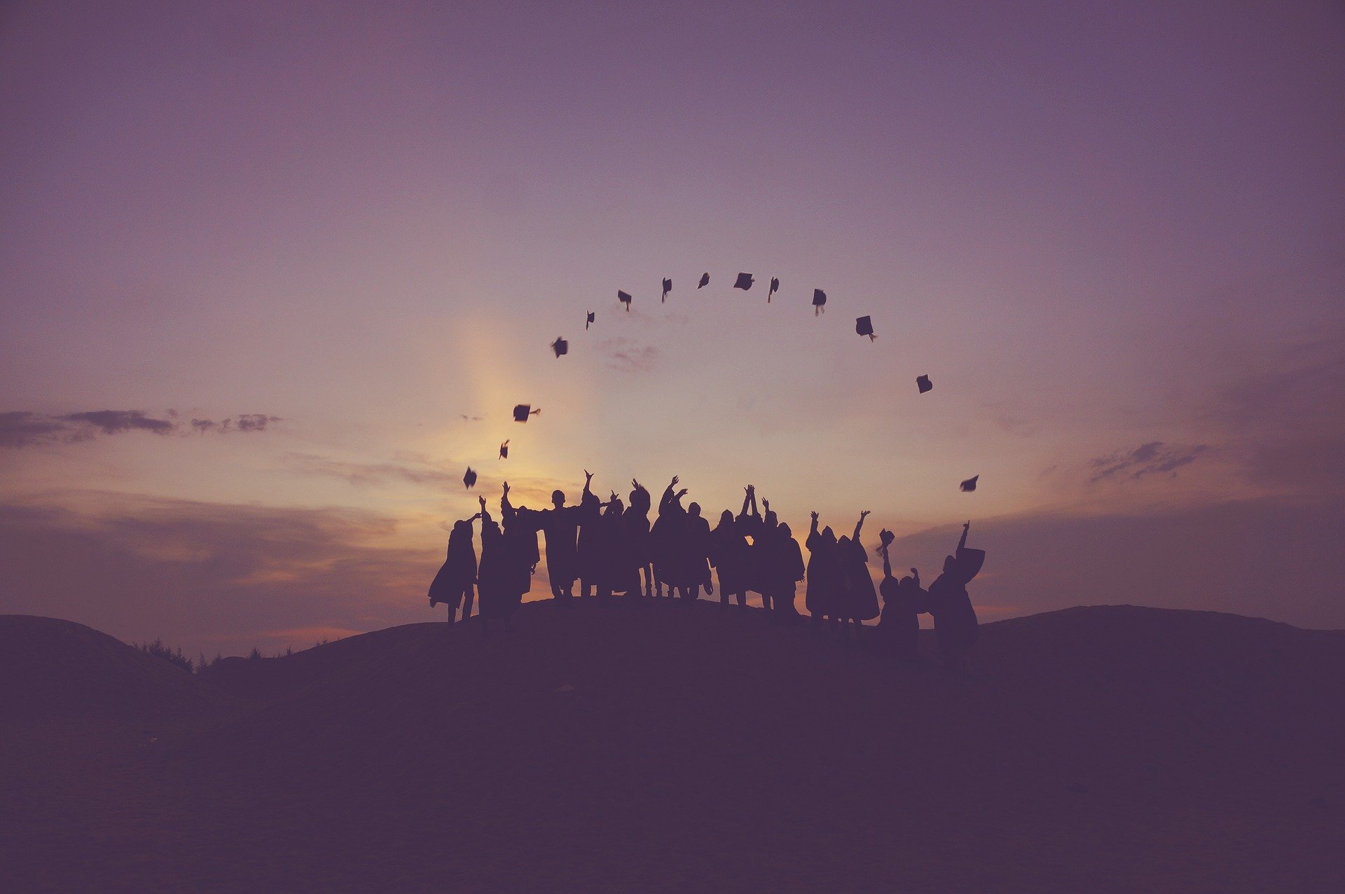 graduates tossing hats at dusk