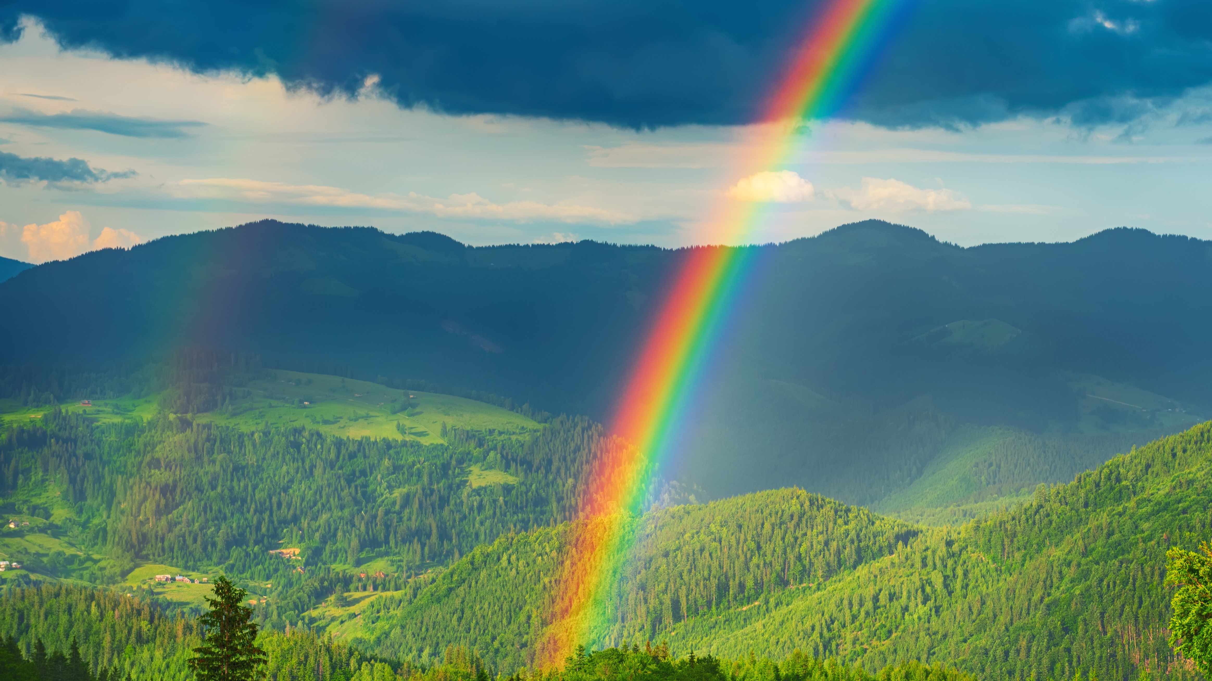 a rainbow with a green background of hills