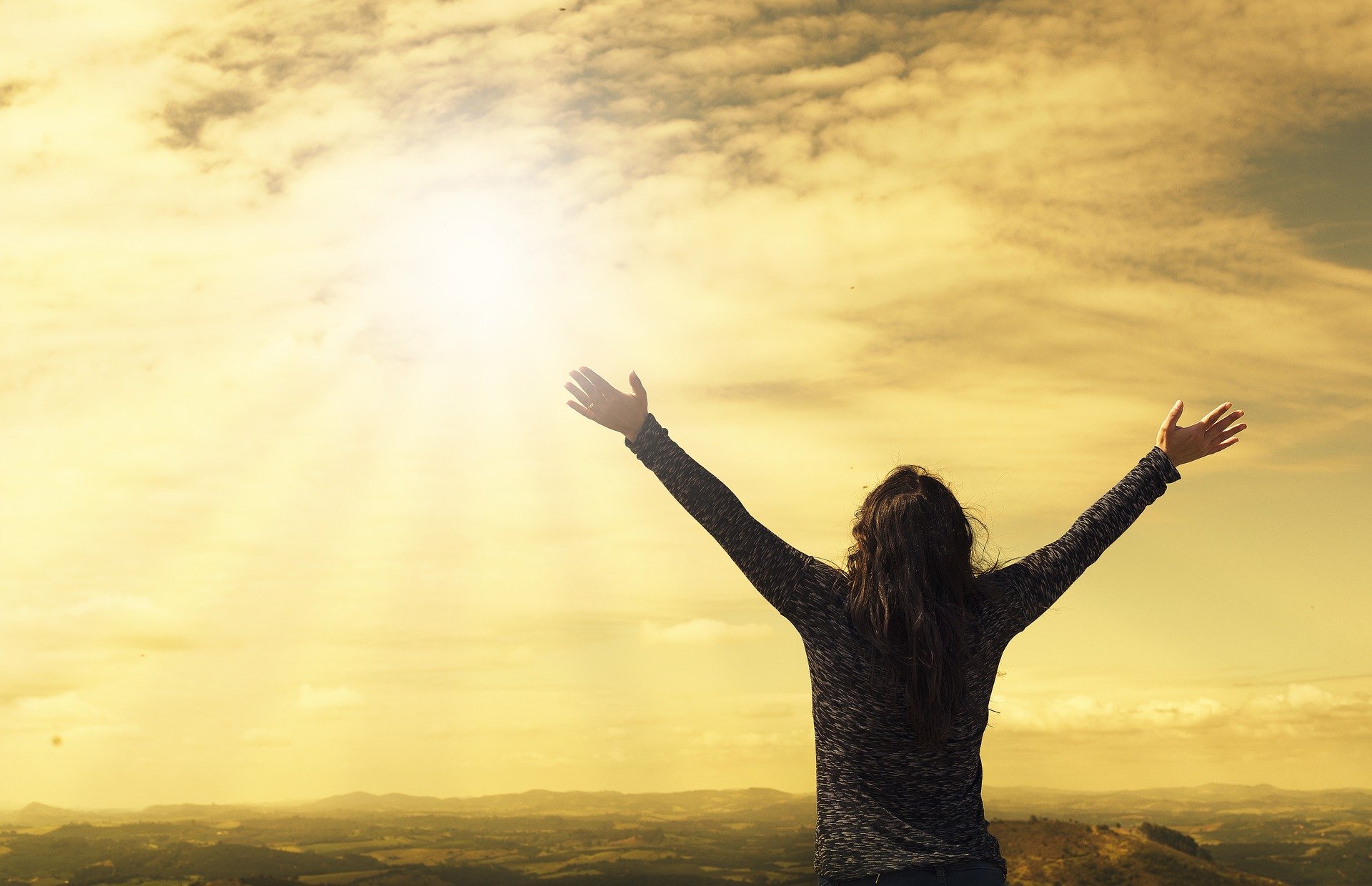 arms raised in V formation, lifted up to the sun -- hope